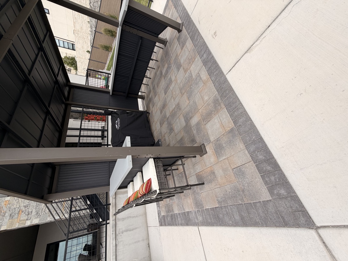 A paver patio with a covered pergola bar and stools