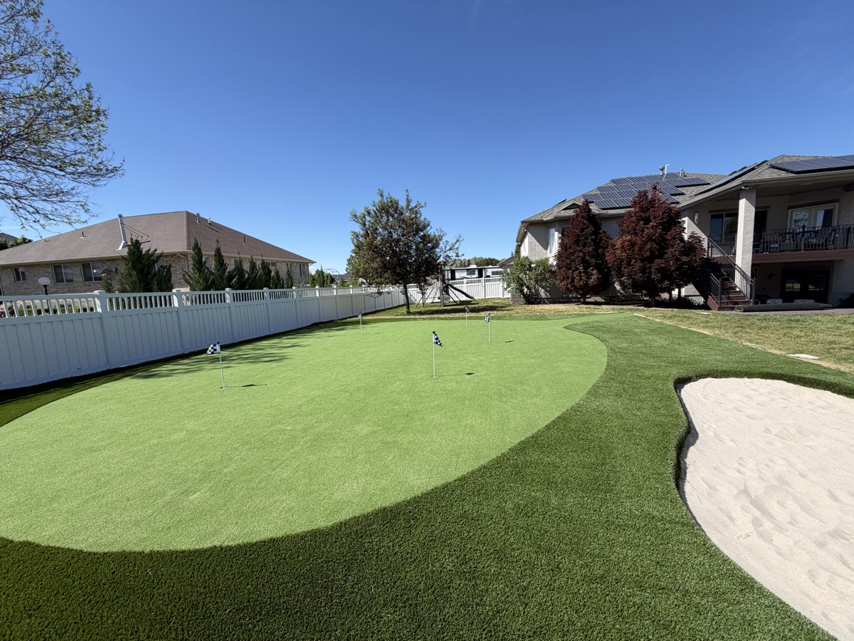 A backyard putting green with a sand bunker